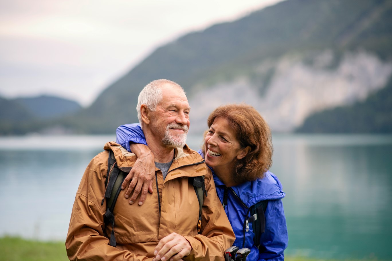 Senior pensioner couple hiking by lake in nature, resting